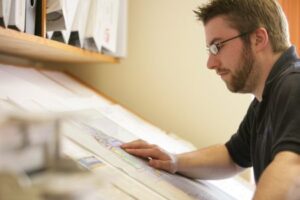 A man looking at a paper design drawing which is on a slanted table.